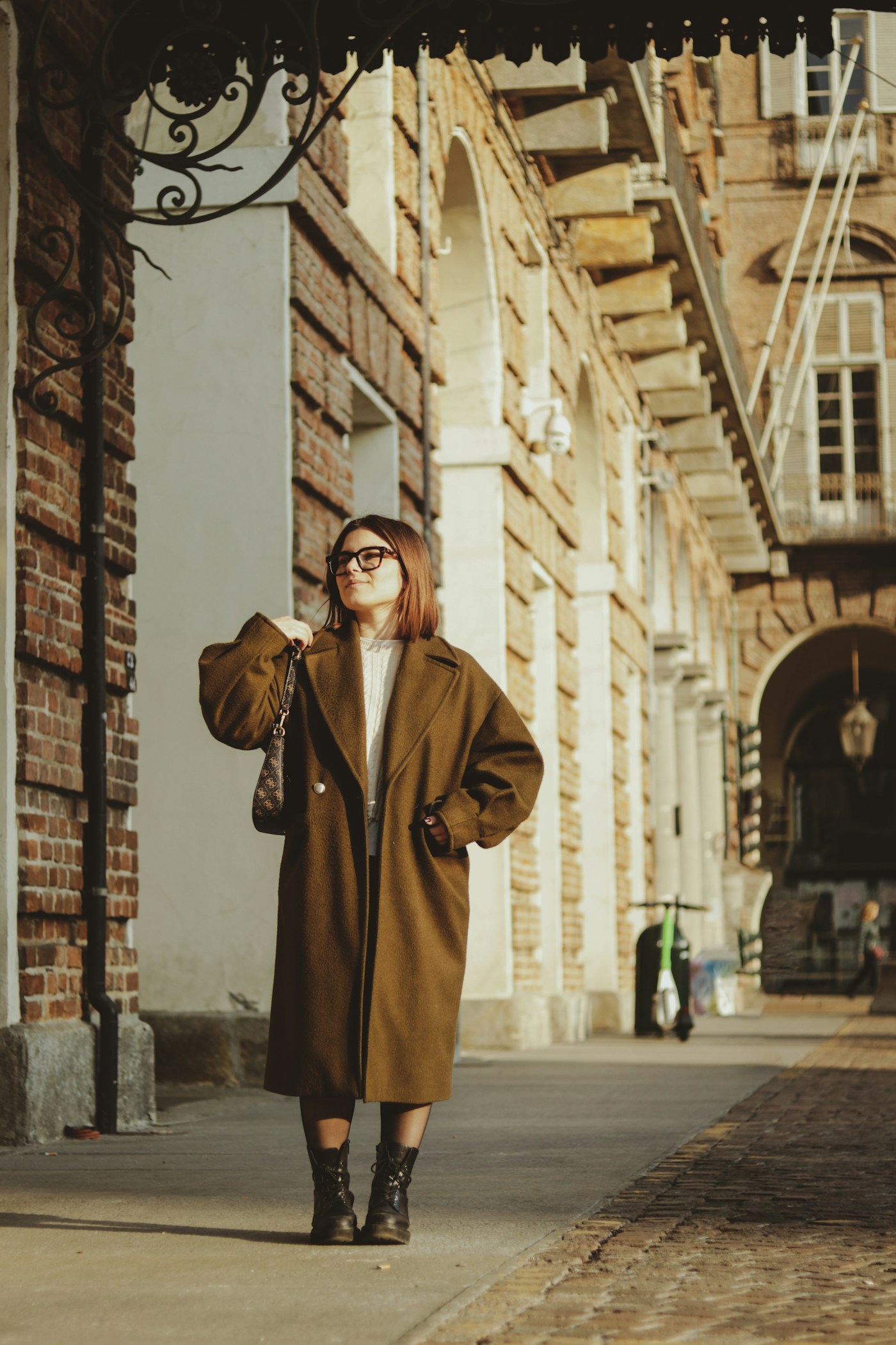 Woman wearing a brown coat on a city sidewalk