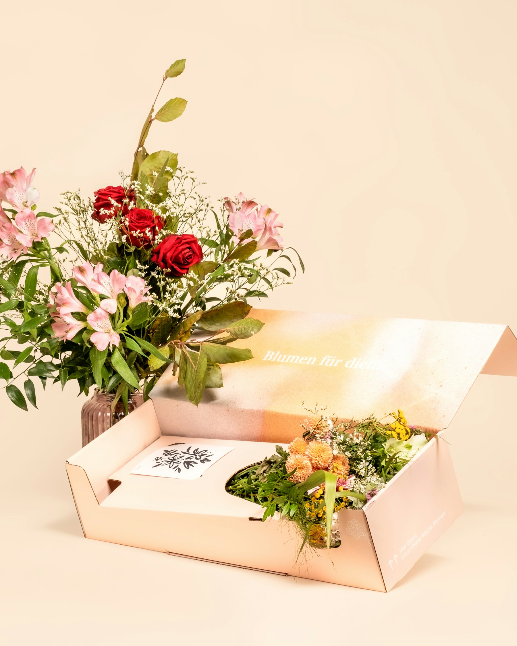 A bouquet of flowers next to an open gift box