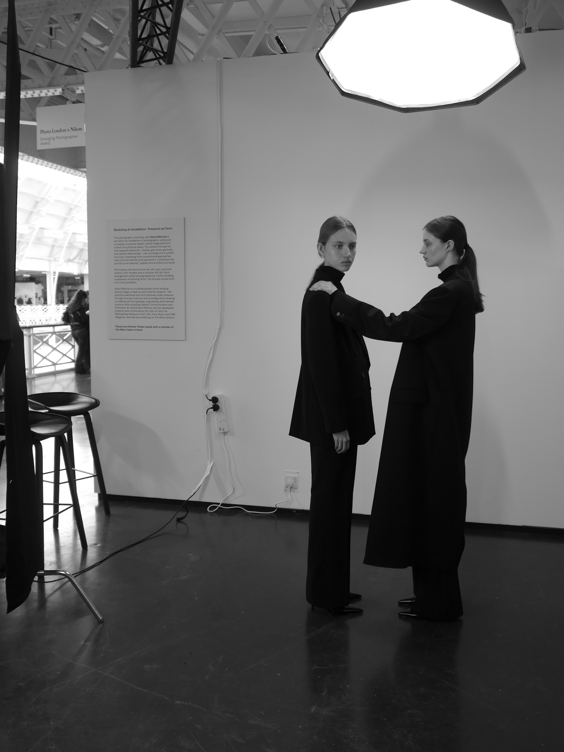 Two models in black outfits posing for a photoshoot