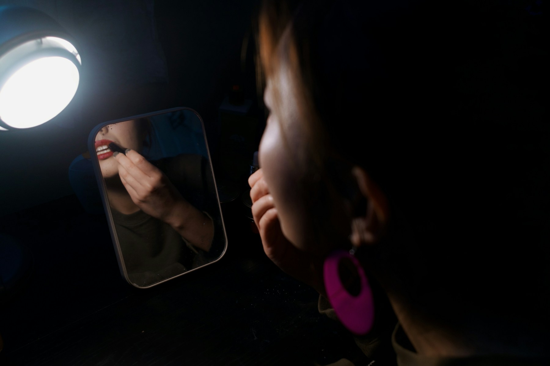 woman facing the mirror putting lipstick on the lips