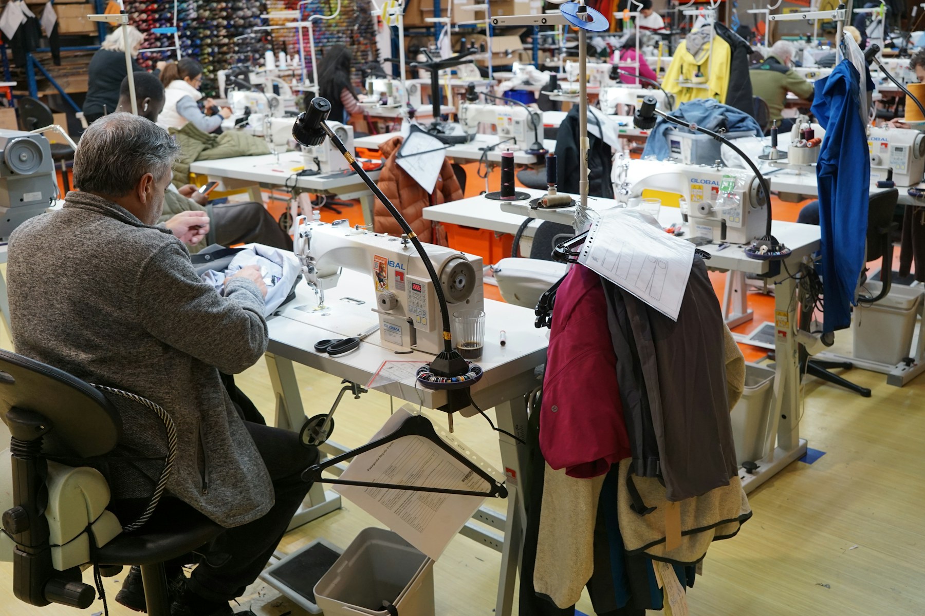 Man sewing at a machine in a busy workshop